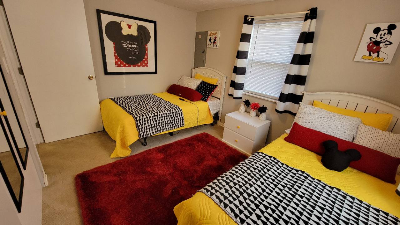 Bedroom with two single beds, yellow bedding, black-and-white blankets and Mickey and Minnie decorations